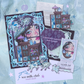 A whimsical mail club titled 'Cabinet of Curiosity' featuring a large illustrated art print postcard, stickers, smaller paper pieces, a purple heart-shaped card, and decorative embellishments on a light blue patterned background.