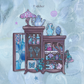 A whimsical illustrated sticker design featuring a dark brown cabinet with blue stained-glass-style panels and shelves filled with pastel purple, blue, and pink objects, set against a pale blue textured background.
