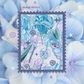 A square stamp sticker design featuring pastel blue, purple, and green floral artwork with a stylized wind chime and stars, centered over a blurred background of pale blue hydrangea-like flowers. Text at the top reads 'stamp sticker'.