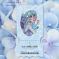 A collectible ticket photocard featuring an anime-style illustration of a teal-haired character, presented against a soft background of blue and white hydrangea flowers. The card is labeled 'sea milk, club' and includes a barcode and the text 'i dreamt in full bloom'.
