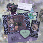 A Halloween witch apothecary themed monthly mail club featuring a whimsical, magical stationery set. The mail set includes a postcard art print, stickers, collectible ticket photocard, love letter, and a self affirmation card.